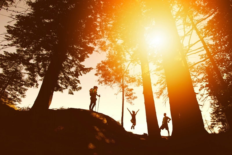 three friends hiking in nature as the sun sets