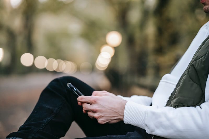 man texts on his phone at the park