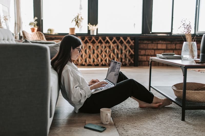 woman working from home on her laptop while sitting on the floor