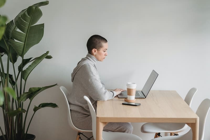 young woman with short hair working on her laptop at the dining table