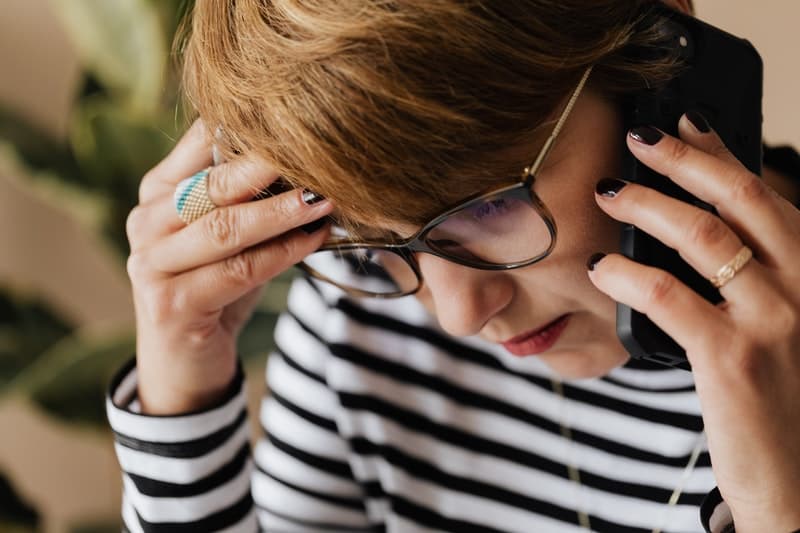 stressed out woman with glasses talks on the phone