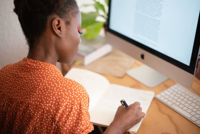 woman writing in a notebook while working at the office