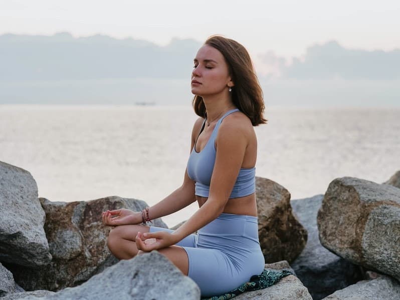 woman meditating on the beach to overcome her self-doubt