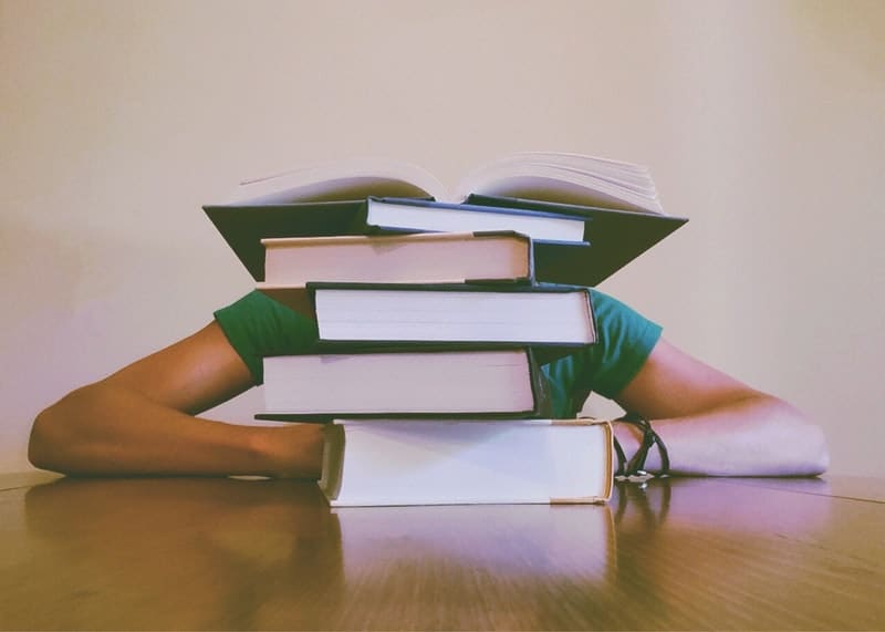 a woman sitting at a desk with a pile of school books