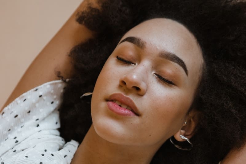 woman with brown hair laying down with her eyes closed