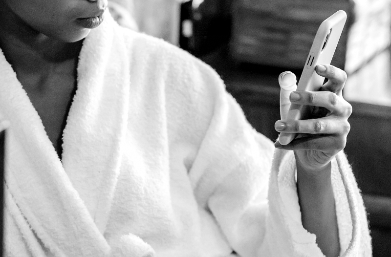 woman in white bathrobe scrolling her phone