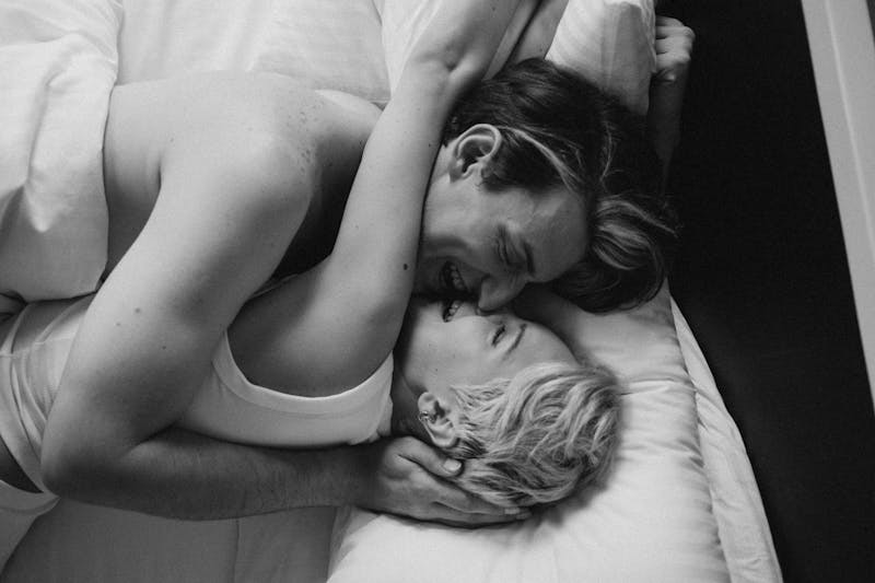 a black and white photo of a couple hugging and laughing in bed