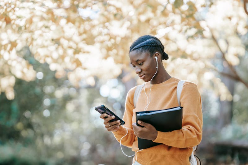 a young woman looks at her phone while walking