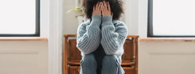 a young woman covers her face with both hands in shame