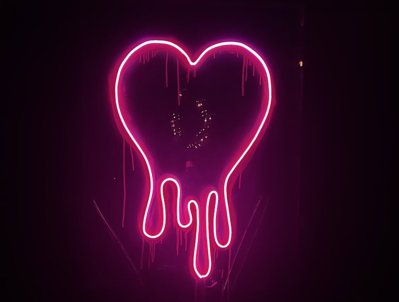 a neon sign showing a pink heart that is melting