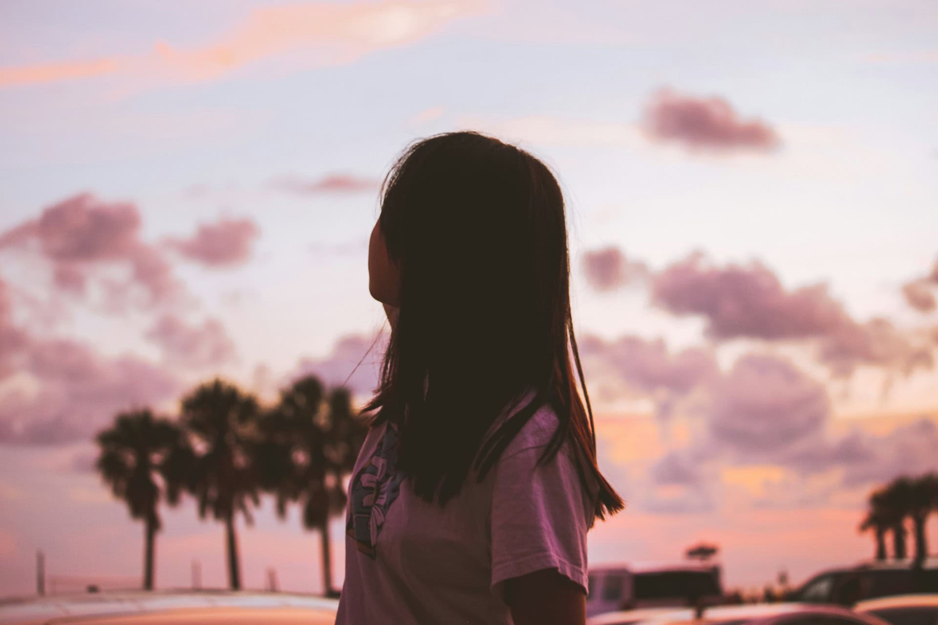 a young woman looks at the pink sunset