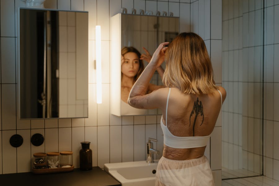 a young woman looks at her reflection in the mirror