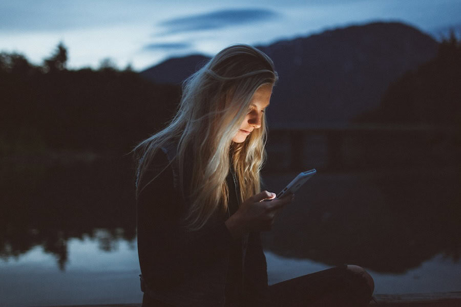 a woman uses her phone in the dark outside