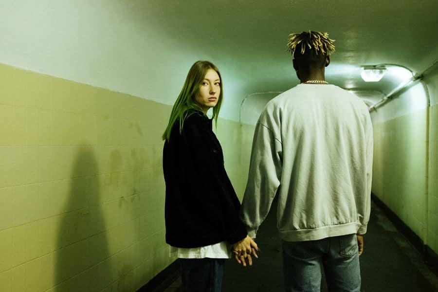a couple is walking in a tunnel holding hands, the woman looks back at the camera